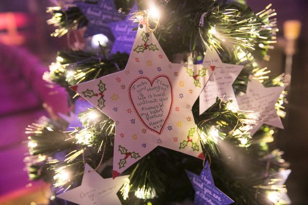 Star decorations hanging on Christmas tree with hand written messages on them.