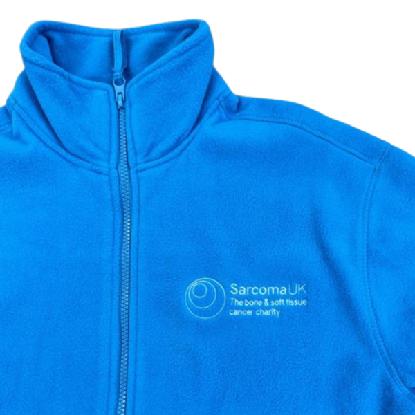 A close up of the logo embroidery on an aqua zip fleece, with the Sarcoma UK logo and tagline 'The bone & soft tissue cancer charity' in white