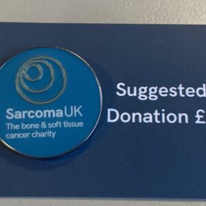 Image containing Sarcoma UK pin badge on a piece of cardboard reading "Suggest donation £2"